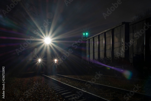 A locomotive with lights on is standing at night on the railway preparing for the departure