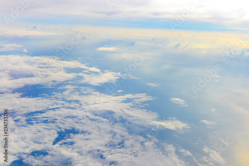 Sun rise in the morning of blue sky above the white clouds and land background with golden light looking through an airplane window