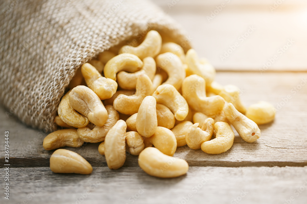 Cashew nuts in burlap bag on wooden gray background . Healthy food Cashew nuts in burlap bag on wooden gray background . Healthy food