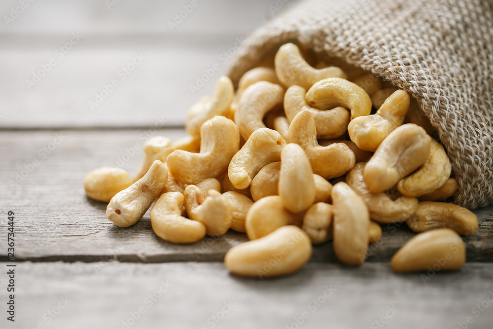 Cashew nuts in burlap bag on wooden gray background . Healthy food Cashew nuts in burlap bag on wooden gray background . Healthy food