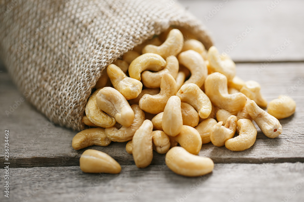 Cashew nuts in burlap bag on wooden gray background . Healthy food Cashew nuts in burlap bag on wooden gray background . Healthy food