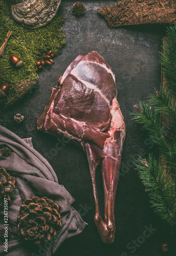 Raw aged leg of venison with bone on dark kitchen table background , top view Fototapet