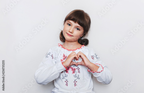 Little Ukrainian girl makes a heart shape with her hands. Love to motherland. Patriotic feelings.