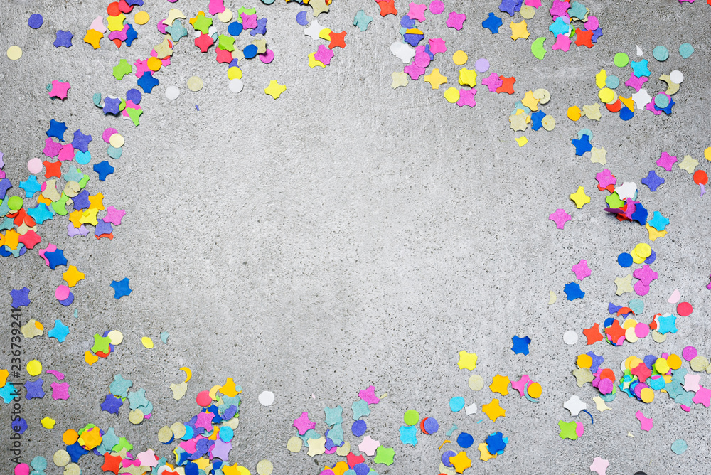 Birthday or holiday background with multicolored confetti on a concrete background. Celebration background with copy space.