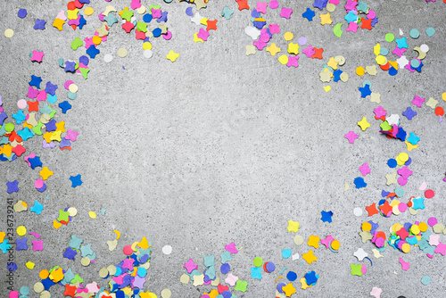 Birthday or holiday background with multicolored confetti on a concrete background. Celebration background with copy space.