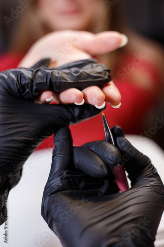 manicurist applying gel lacquer coat on client's nails. beauty, make up, manicure, nail art concept