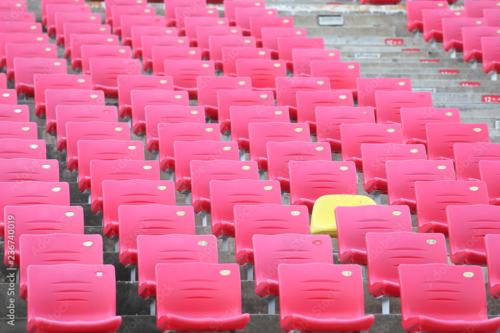 Obraz premium Czerwone siedzenia i jedno żółte tło stadionu siedzenia