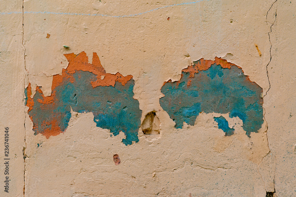 an old painted wall with pealing blue and orange paint