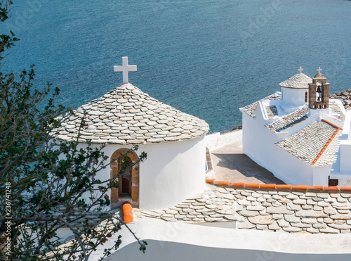 The white Church Panagitsa of Pyrgos with stone tile on Skopelos island against the blue sea of city bay photo