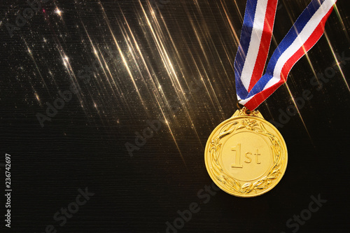 top view image of gold medal over black background. Glitter overlay.