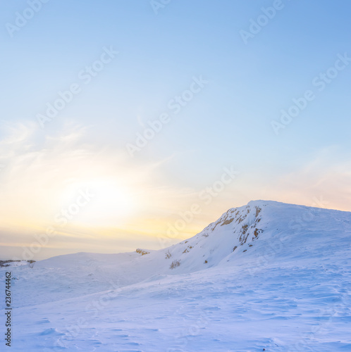 hill among a winter snowbound plains at the sunset