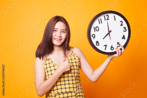 Young Asian woman thumbs up with a clock.