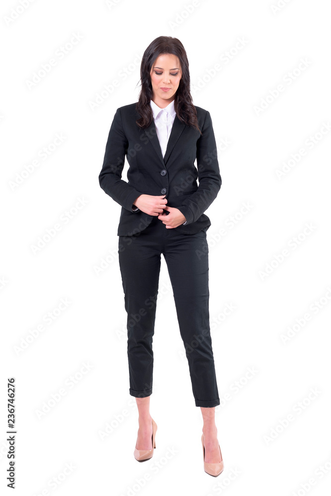 Relaxed young business woman unbuttoning black suit looking down. Full body isolated on white background. Relaxed young business woman unbuttoning black suit looking down. Full body isolated on white background.