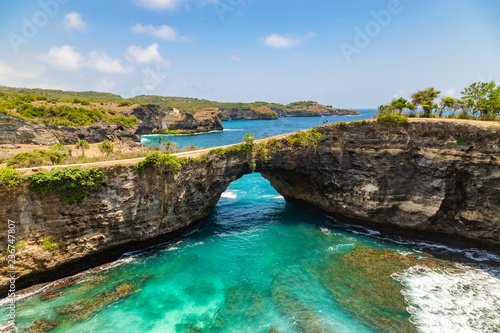 Beautiful landscape of a Broken Beach, located in Nusa Penida Island, the southeast island of Bali, Indonesia. The amazing tourist attraction of the rock, cliff, mountain, and ocean waves. © umike_foto