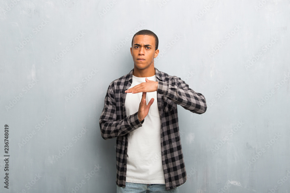 Young african american man with checkered shirt making stop gesture with her hand to stop an act