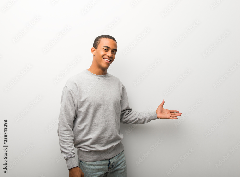 African american man on white wall background pointing back and presenting a product African american man on white wall background pointing back and presenting a product
