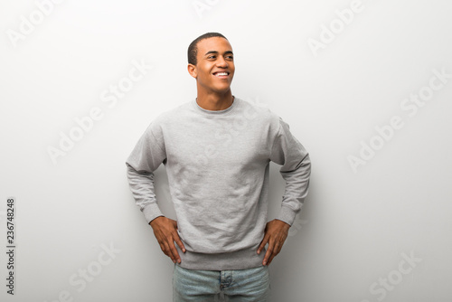 African american man on white wall background posing with arms at hip and laughing