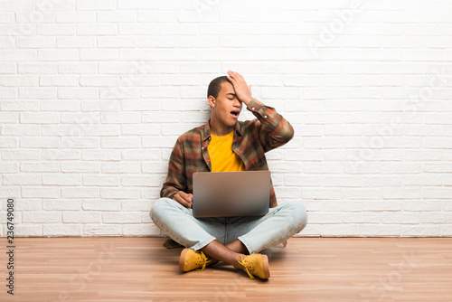 African american man sitting on the floor with his laptop has just realized something and has intending the solution