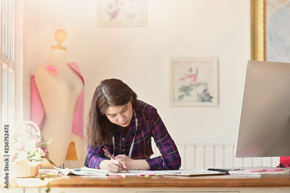 Stylish Asian fashion designer working sketch in atelier. Stylish Asian fashion designer working sketch in atelier.