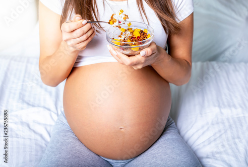 Gesunde Ernährung in der Schwangerschaft: schwangere Frau hält eine Schüssel mit Müsli in der Hand