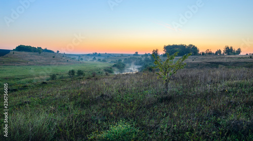 Tranquil summer landscape with river curve and meadow.