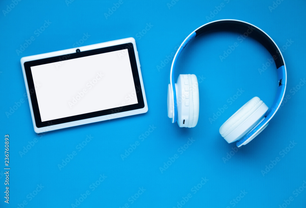 Headphones and tablet on a blue background. Headphones and tablet on a blue background.