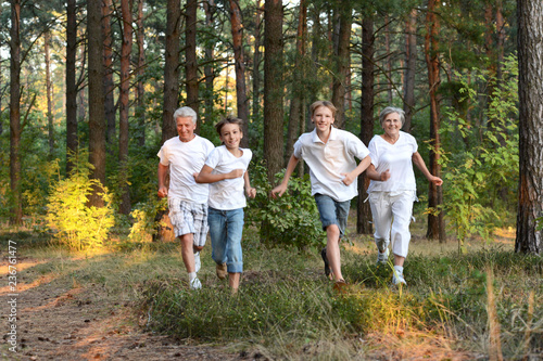 Cheerful boys with his grandparents having fun in summer forest