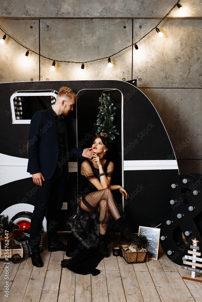 The concept of the Christmas party. Stylish couple in love in black man and woman hugging on the background of dark Christmas decor. The concept of the Christmas party. Stylish couple in love in black man and woman hugging on the background of dark Christmas decor.