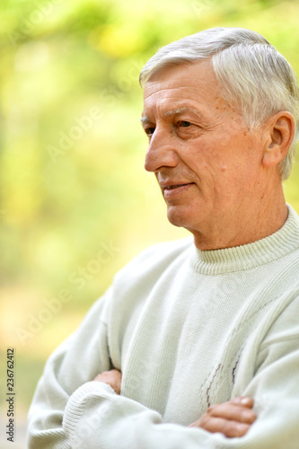 Portrait of thinking senior man on autumn background