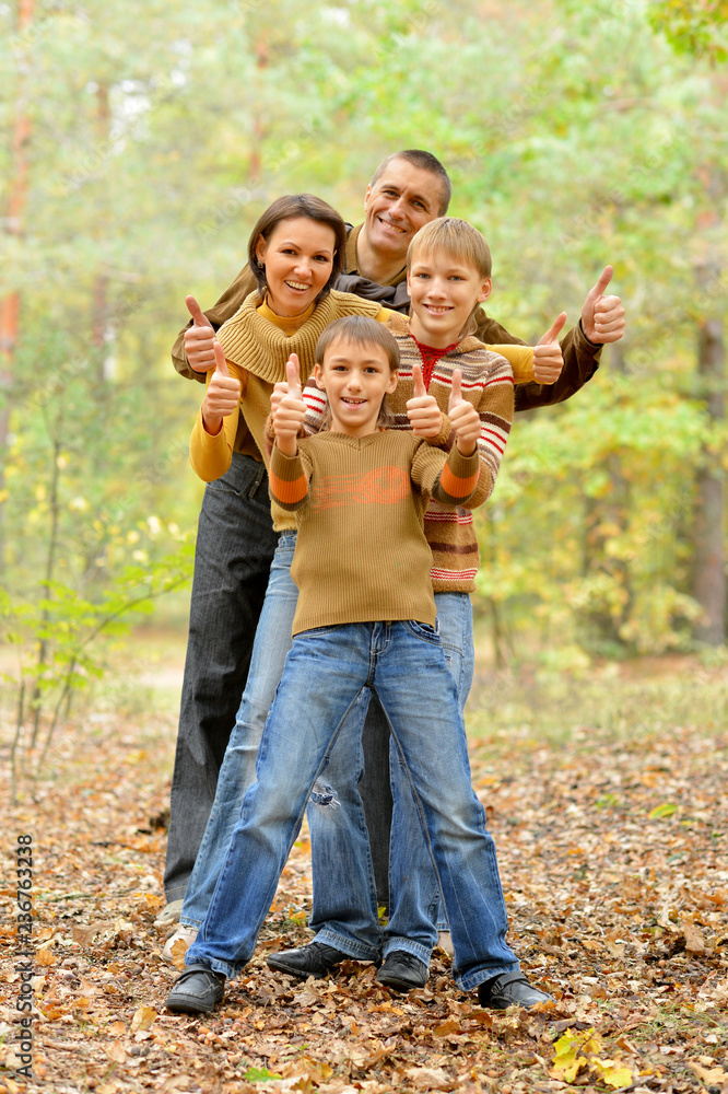 Naklejka premium Portrait of family of four showing thumbs up in autumn forest