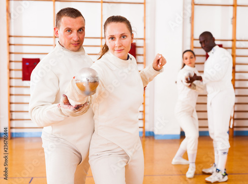 Woman practicing new movements with trainer at fencing room
