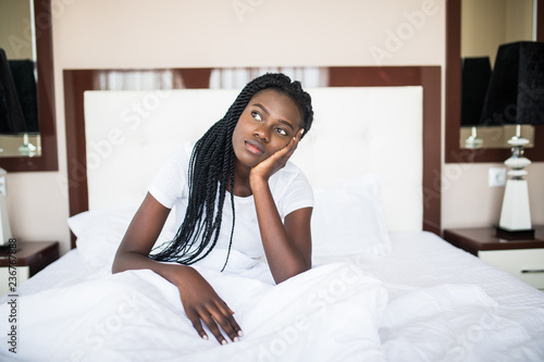 Young african Woman sitting on her bed looking bored or sleepy at the camera