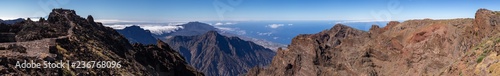 Wide panorama from the top of the mountain to the crater of the volcano. Background canyon with clouds and ocean