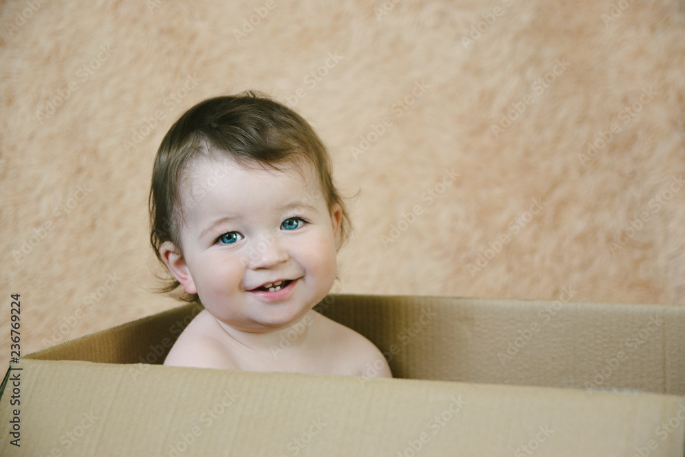 Small naked child sitting in a cardboard box and smiles Small naked child sitting in a cardboard box and smiles