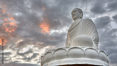 Gautama buddha sculpture on the cloud sky background at sunset time