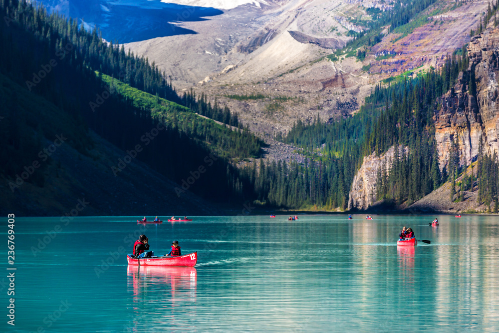 Fototapeta Banff, Canada - Sept 17th 2017 - A family doing kayak at the Lake Louise with pine trees in the background at the Banff National Park in Canada