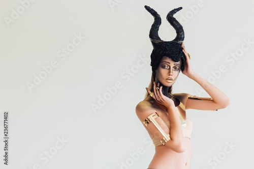 The model wears a hat of Maleficent and has makeup in the Halloween theme. She is posing And there is space behind the text.