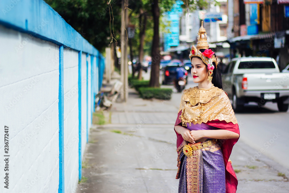 Woman wearing Thai style dress standing on the footpath in Bangkok, Thailand.