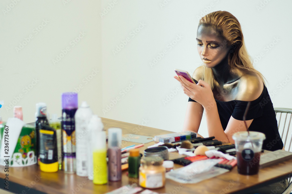 Model is playing mobile phone during a break and waiting for a makeup artist. Model is playing mobile phone during a break and waiting for a makeup artist.