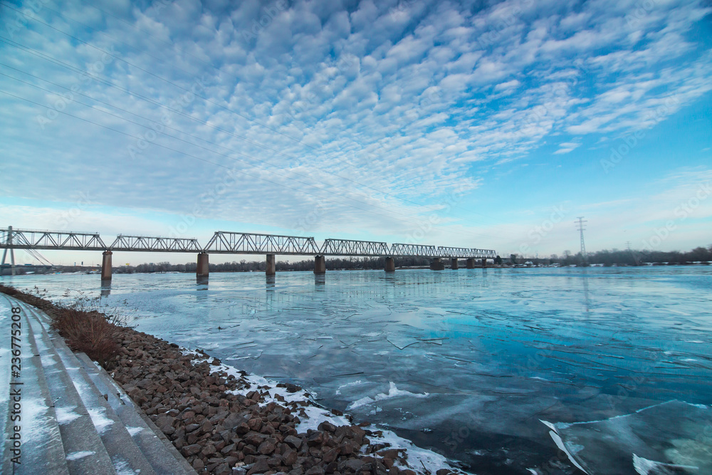 Railway bridge across Dnipro with beautiful cloudy sky in Kyiv, Ukraine
