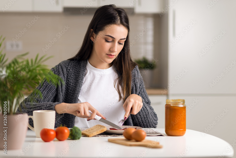 Young woman having breakfast at dining table in the morning Young woman having breakfast at dining table in the morning