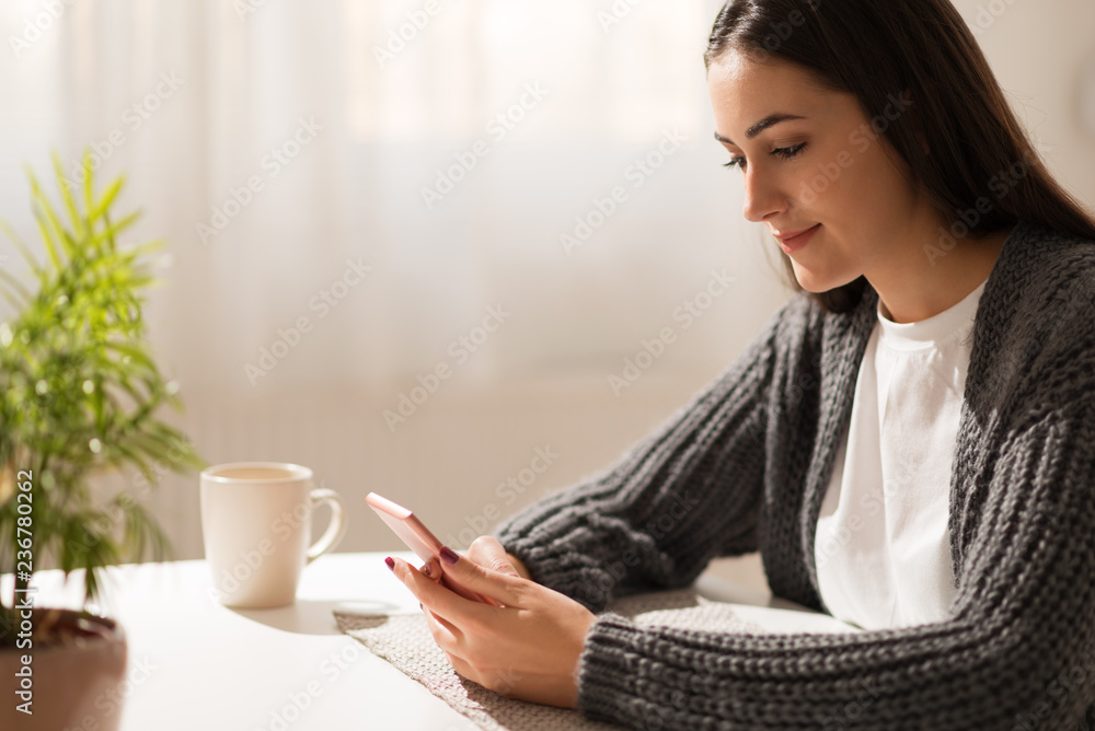 Young woman reading a text message on cell phone at home Young woman reading a text message on cell phone at home