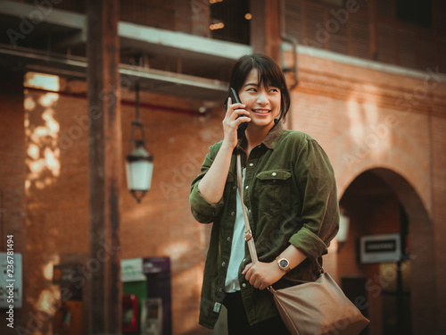 Asian woman using smartphone with happy mood in shopping mall