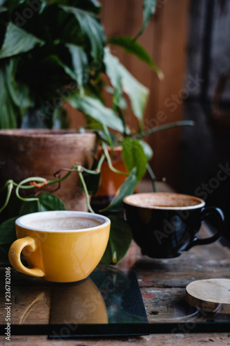 Yellow and black cups with coffee on wooden table