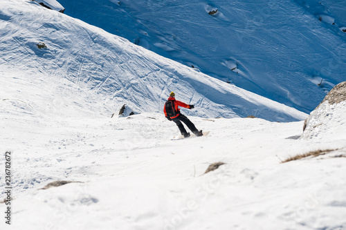 Chamonix de Mont Blanc, France, December 24, 2015. A snowboarder wearing a bright red vest descending from the Plan de l'Aiguille towards Chamonix. The chamonix area is well known for outdoor sports.