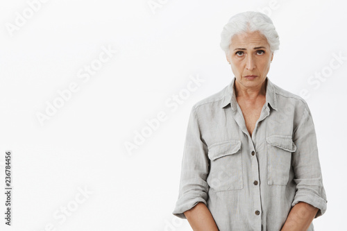 Obraz na płótnie Indoor shot of sad and gloomy cute grandmother with gray hair frowning looking w