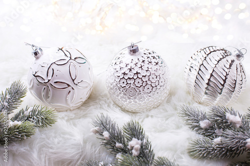  Three white balls  and fir tree branches on white fur background.