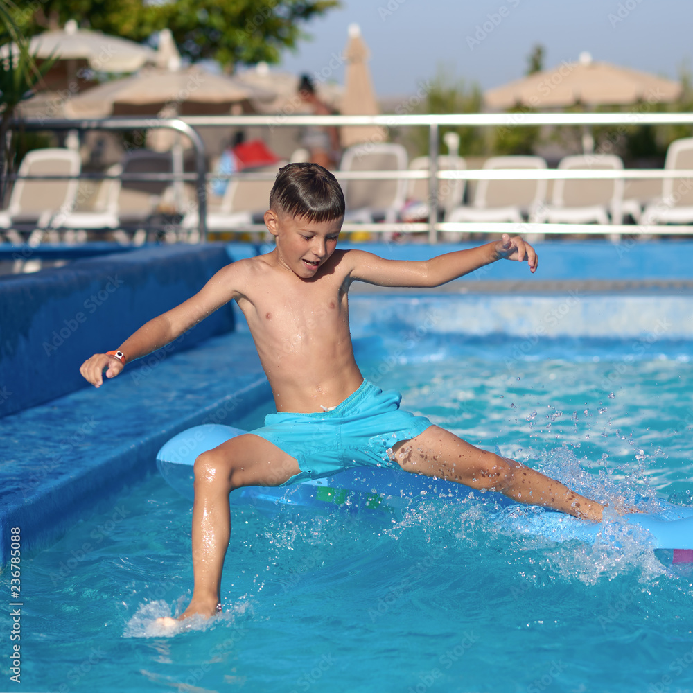 Caucasian boy having fun making fantastic jump into swimming pool at resort. His arms and legs are wide open.