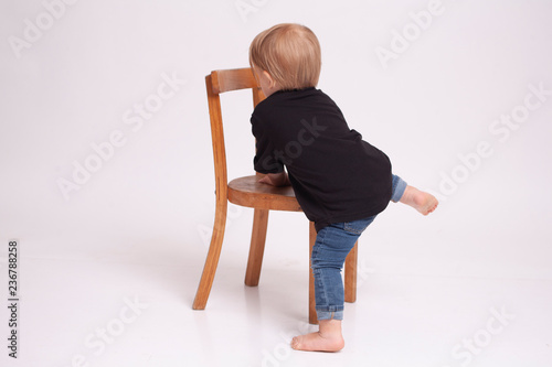 fair-haired boy with a chair in a white studio