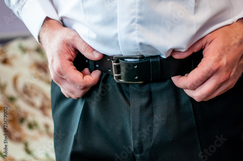 Man correcting belt on trousers